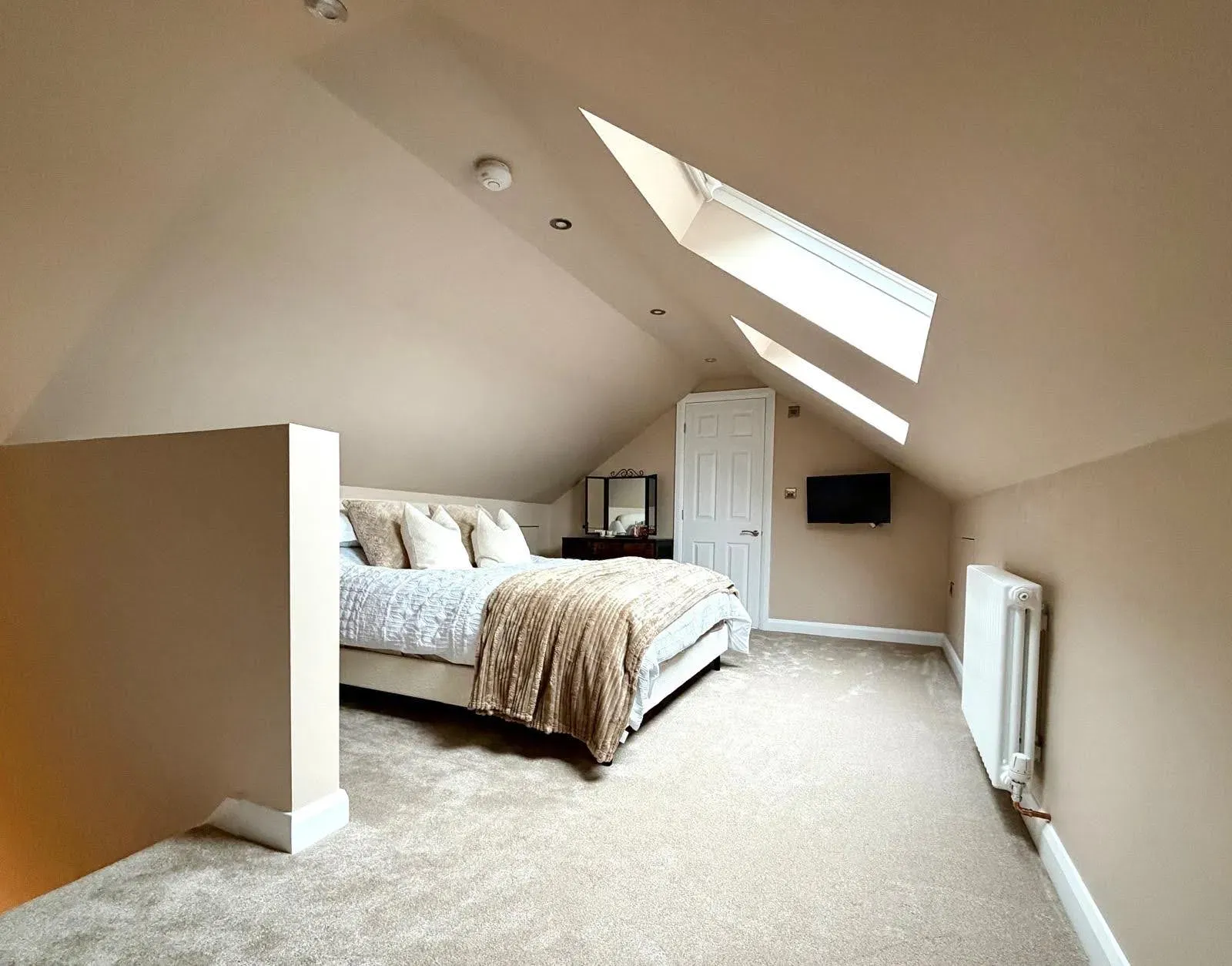 Bright attic bedroom with a sloping ceiling and roof windows